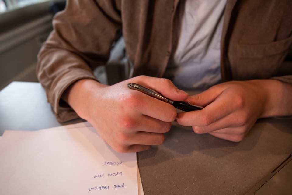 A person's hands holding a pen over a part-completed paper form on a desk