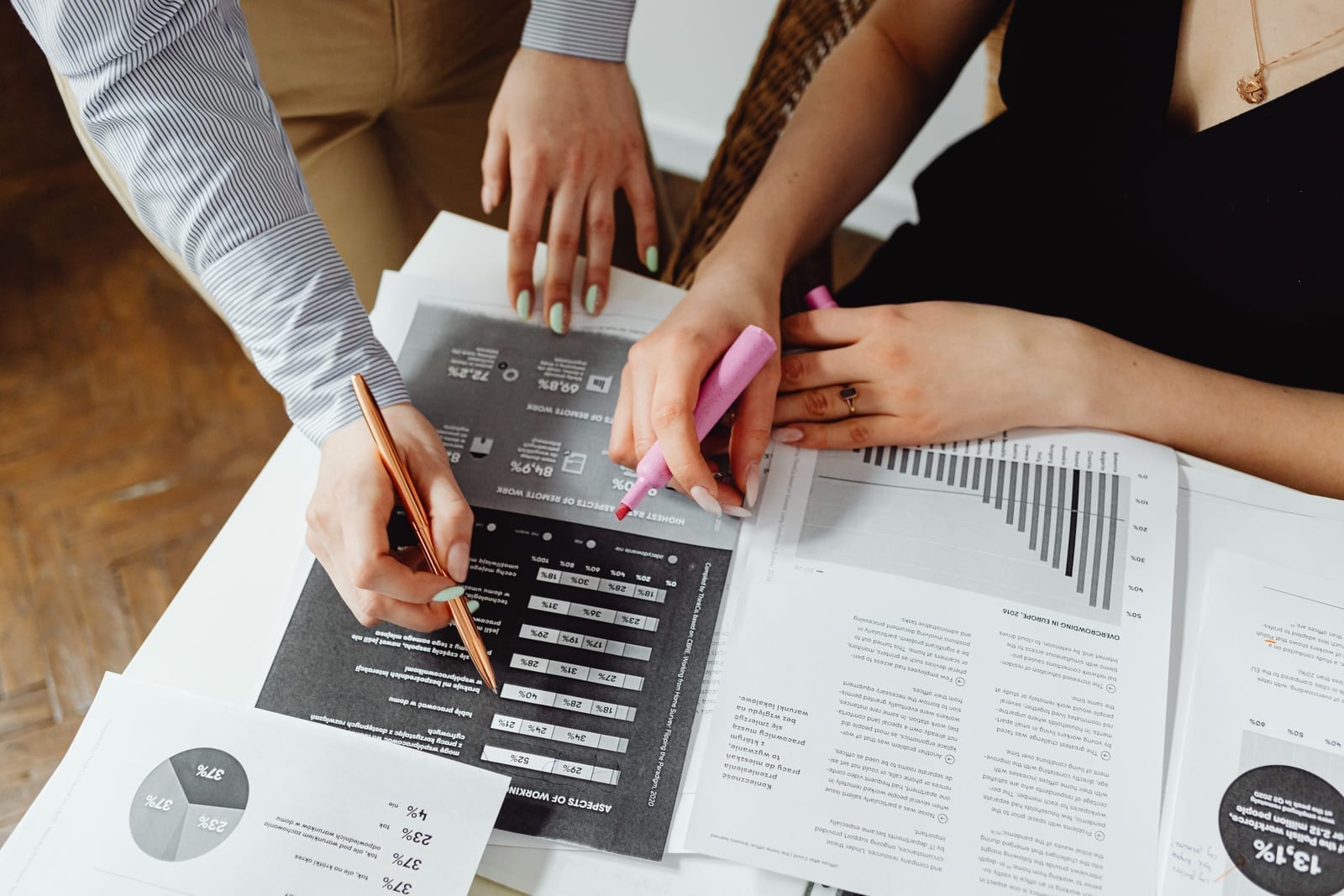 Hands reviewing financial documents and charts spread across a desk