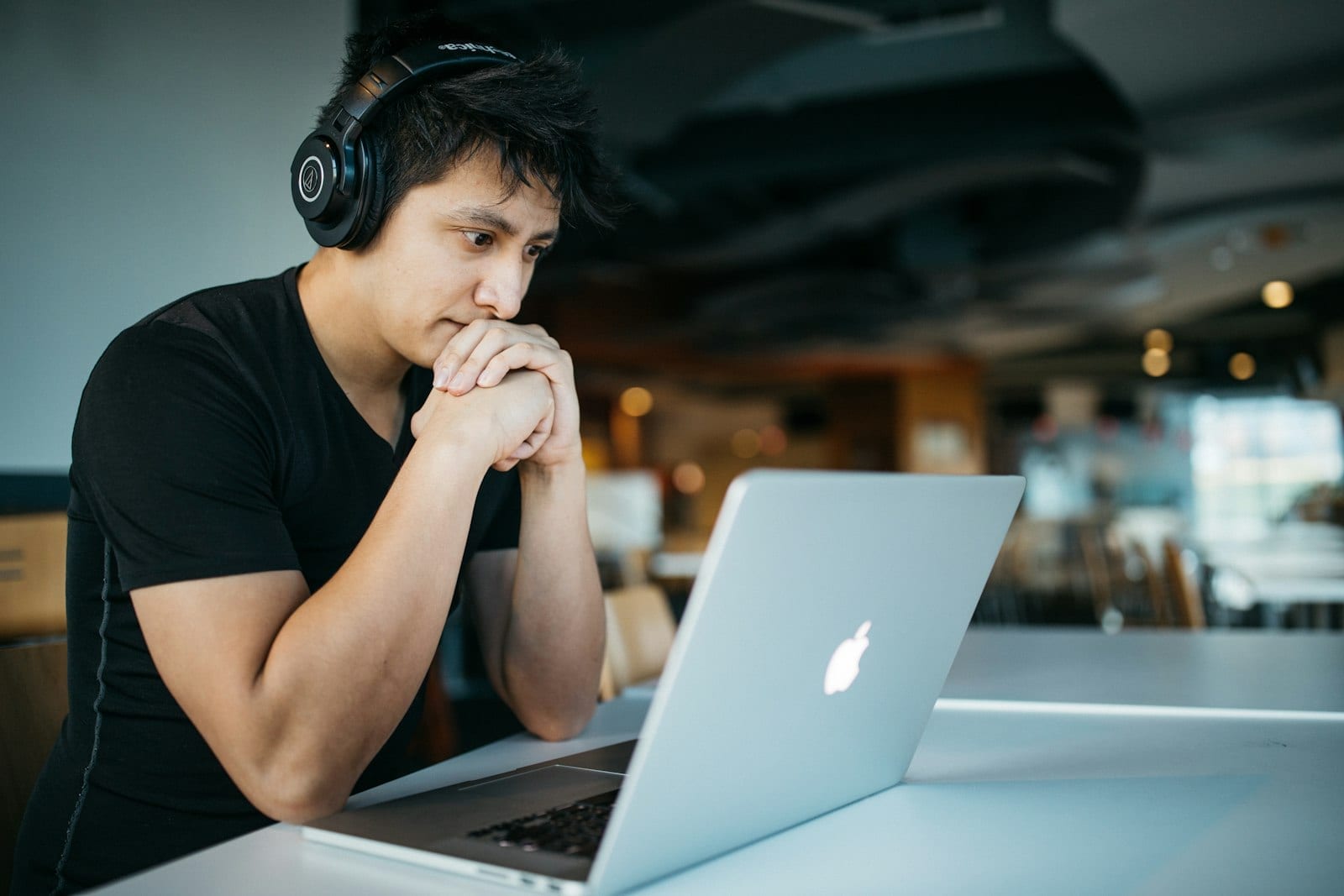 A person working through coursework on a laptop while wearing headphones