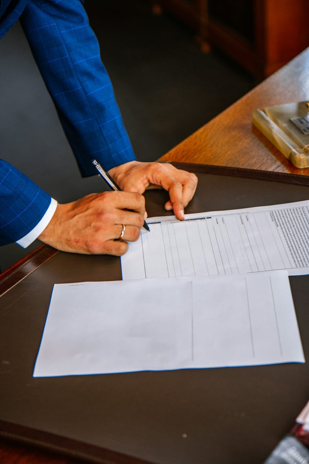 Close-up of a hand signing a white form document