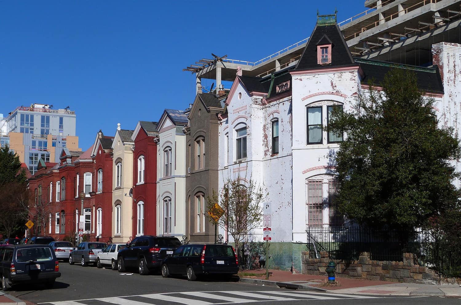 A terrace of brick and painted rowhouses with bay fronts and short front stoops along Wallach Place NW in Washington, DC