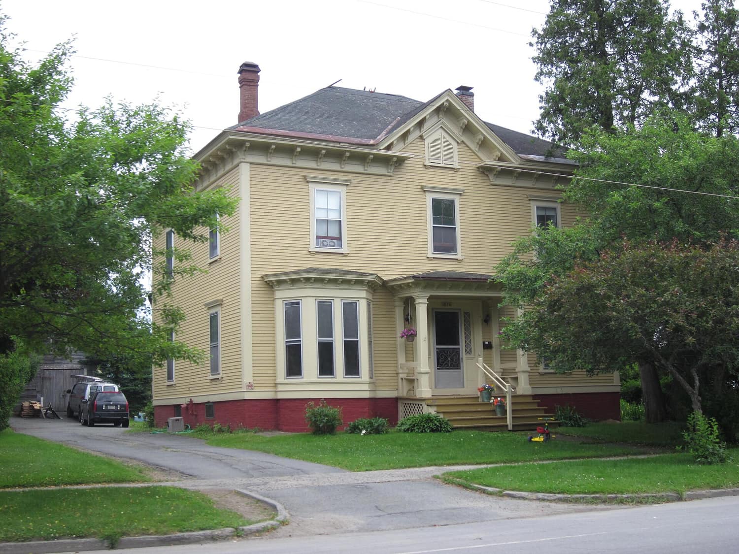 A white clapboard house with black shutters and a covered porch on Main Street in St. Johnsbury, Vermont